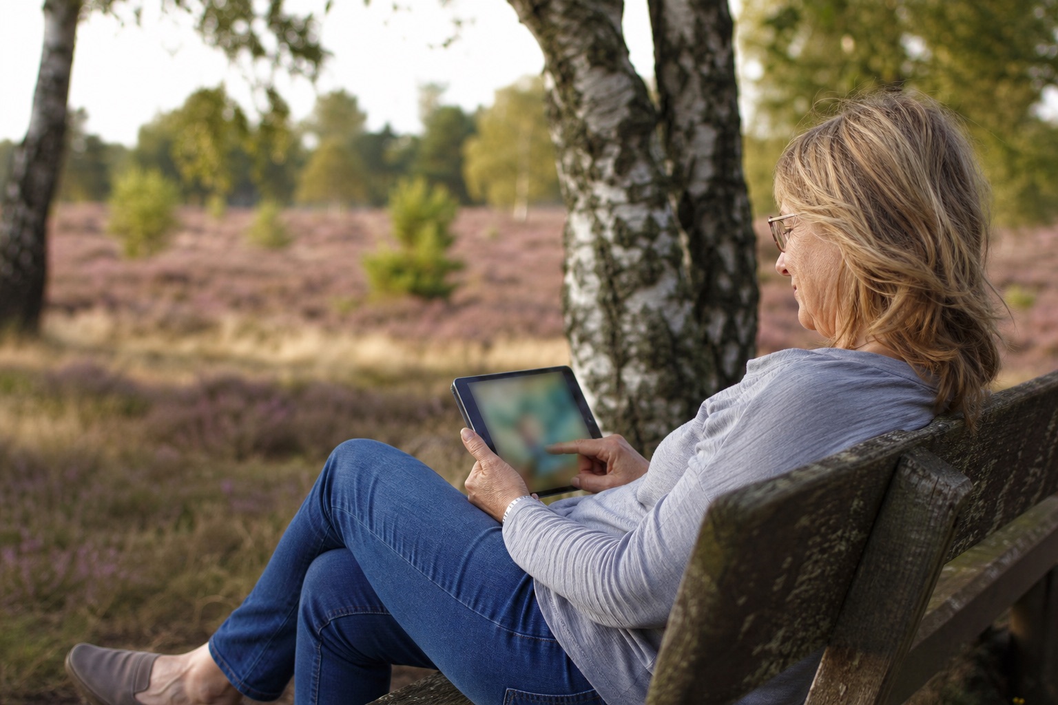 Person löst ein Rätsel auf dem Tablet in der Heide